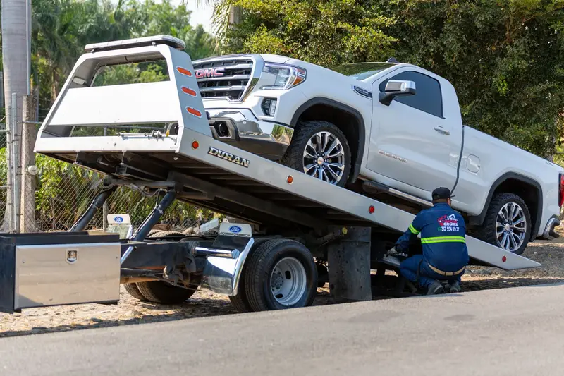 A pickup truck being loaded onto a flatbed carrier
